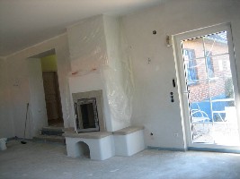 neues Wohnzimmer mit Blick auf Kachelofen, links der Durchgang zum  Altbau